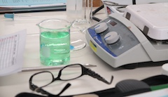 A desk in a science lab with eye glasses and a beaker.