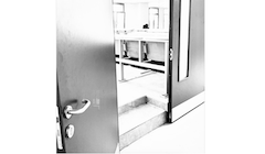 A black and white image of an open classroom door with students inside.